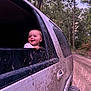 Bailey is registered to the contest to win money with this photo: baby, child, car, muddy_car, window, forest, trees, dirt_road, outdoor, happy, smiling, vehicle, tire, nature, adventure, exploration, mud, transportation, young_child, daylight