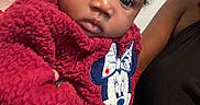 Nova joined the competition — help win amazing prizes! baby, child, infant, portrait, close_up, face, eyes, looking_at_camera, red_outfit, fleece, mickey_mouse, cartoon_character, bow, sitting, adult, arm, indoor, home, family, cute