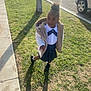 child, girl, outdoor, grass, sidewalk, coat, skirt, shadow, sunlight, car, street, happy, playful, white_coat, black_shoes, curly_hair, portrait, daytime, casual, smiling
