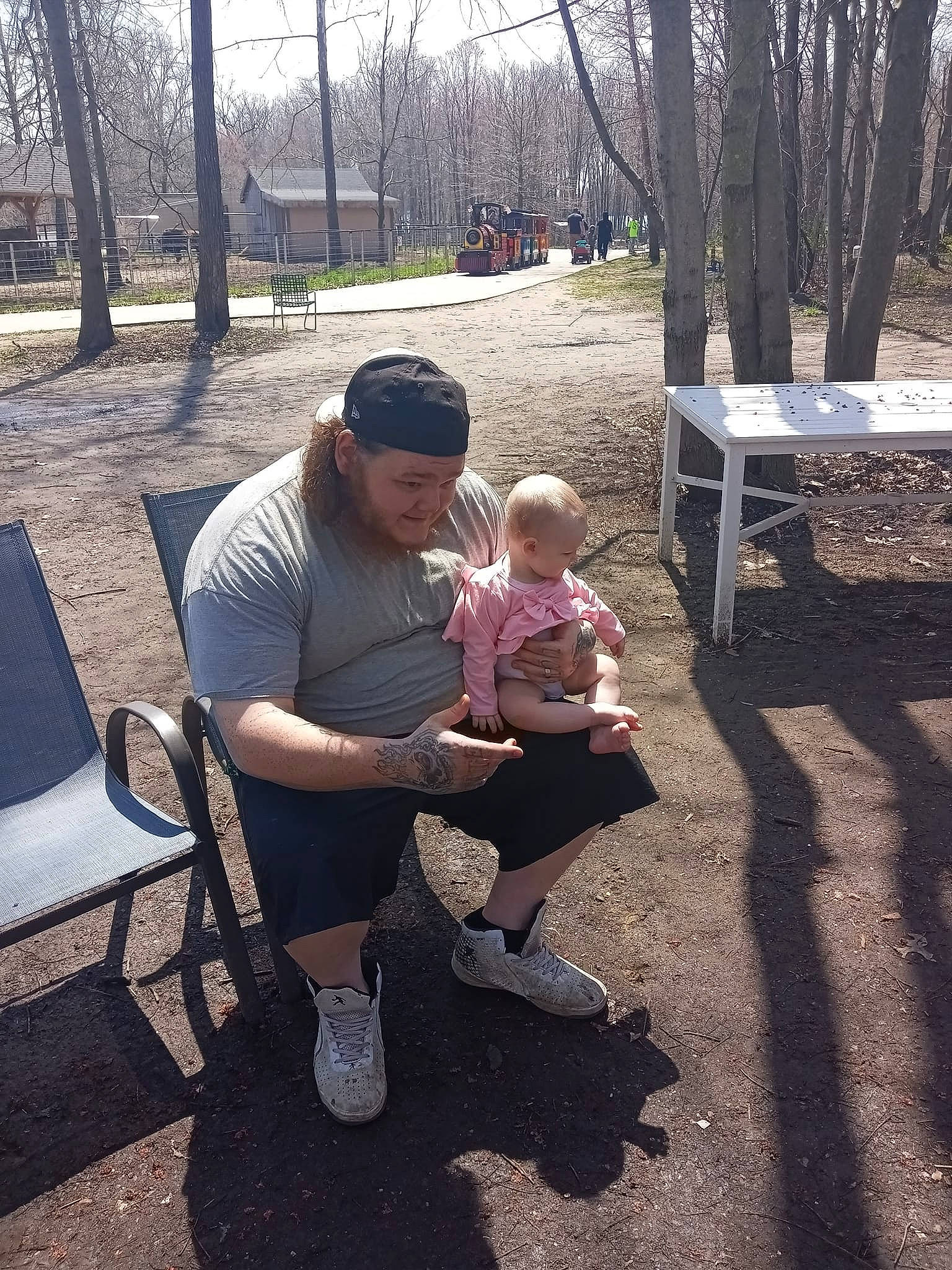 Lorraine joined the competition — help win amazing prizes! baby, bench, chair, child, event, eyewear, fun, grass, hat, headwear, lap, leisure, outdoor_furniture, person, plant, recreation, sitting, soil, toddler, tree