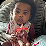 baby, bib, blanket, child, clothing, couch, cozy, curious, expression, face, food_pouch, hair, hand, happy_baby, holding, indoors, organic_food, person, sitting, toddler