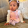baby, child, girl, infant, couch, sofa, hair_clips, pink_clothing, purple_socks, cute, indoor, portrait, seated, curious, expression, cozy, home, furniture, young_child, adorable