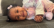 Anova is registered to the contest to win money with this photo: baby, casual, child, closeup, couch, cozy, cute, face, hair_accessories, hands, happy, indoor, infant, pink_clothing, portrait, relaxed, seated, smiling, soft_lighting, young_child