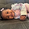 Anova is registered to the contest to win money with this photo: baby, child, smiling, cute, pink_clothing, hair_accessories, couch, indoor, portrait, young_child, hands, face, happy, relaxed, infant, seated, closeup, cozy, soft_lighting, casual
