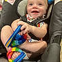 Klay-Cee is registered to the contest to win money with this photo: baby, child, smiling, car_seat, straps, rainbow_slippers, feet, hands, happy, cute, indoor, infant, clothing, playful, person, portrait, closeup, seat, toy, footwear