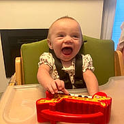 Klay-Cee joined the competition — help win amazing prizes! baby, high_chair, toy, giraffe, piano_toy, smiling, happy, child, indoor, green_chair, table, playing, infant, person, cute, hand, face, expression, joy, clothing
