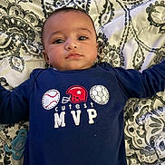 Saint joined the competition — help win amazing prizes! baby, infant, child, onesie, clothing, blue_clothing, face, head, lying_down, bedspread, pattern, pacifier, hand, arm, person, indoor, cute, young, portrait, expression