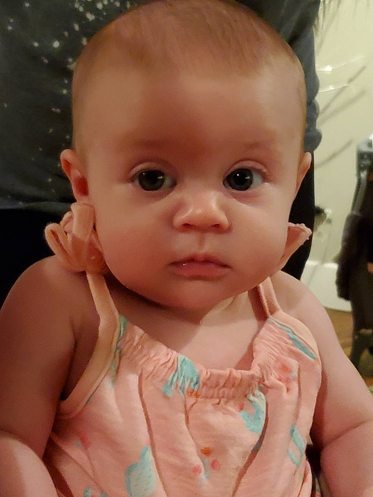 Addison is registered to the contest to win money with this photo: baby, baby_toddler_clothing, cheek, chin, dress, ear, eyebrow, eyelash, facial_expression, finger, gesture, hairstyle, hand, iris, lip, mouth, neck, nose, person, pink