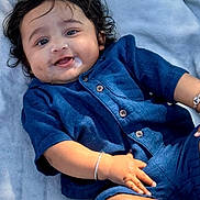 Shaurya is registered to the contest to win money with this photo: baby, infant, child, blue_outfit, bracelet, curly_hair, dimples, drool, blanket, smiling, happy, cute, portrait, young_child, lying_down, skin, face, hand, outdoor, soft_texture