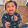 Shaurya is registered to the contest to win money with this photo: baby, child, smiling, toy, black_clothing, dimples, face, hand, outdoor, sunlight, happy, cute, infant, sitting, portrait, person, bright, background, woven_chair, playful