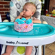 Riverlyn joined the competition — help win amazing prizes! baby, high_chair, cake, pink_cake, blue_frosting, sprinkles, baby_trend, brick_wall, outdoor, party, snacks, table, hand, foot, curious, sucking_thumb, celebration, infant, person, food