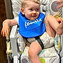 Riverlyn is registered to the contest to win money with this photo: baby, high_chair, bib, food, messy, child, smiling, indoor, cushion, pattern, hand, foot, clothing, seat, happy, infant, face, person, cute, feeding