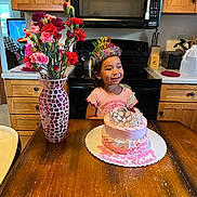 Alina joined the competition — help win amazing prizes! child, birthday, cake, tiara, flowers, vase, table, kitchen, oven, microwave, wooden_cabinet, smile, pink, party_hat, celebration, girl, happy, decor, indoor, person