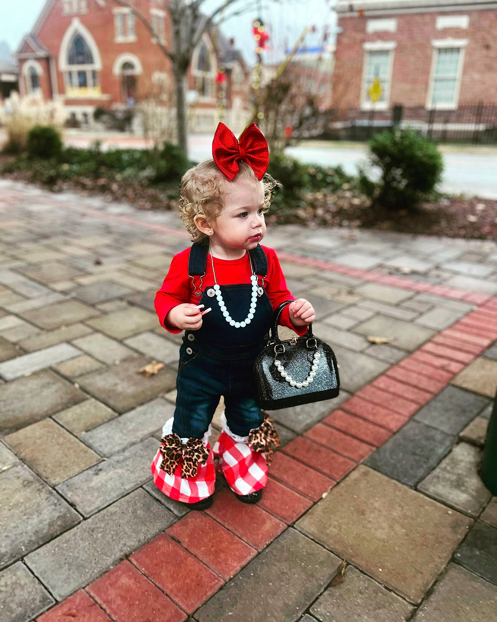 Paizley is registered to the contest to win money with this photo: baby_toddler_clothing, carmine, child, dress, fictional_character, flooring, grass, pattern, person, plant, red, road_surface, sidewalk, sitting, standing, street, toddler, toy, tree, window