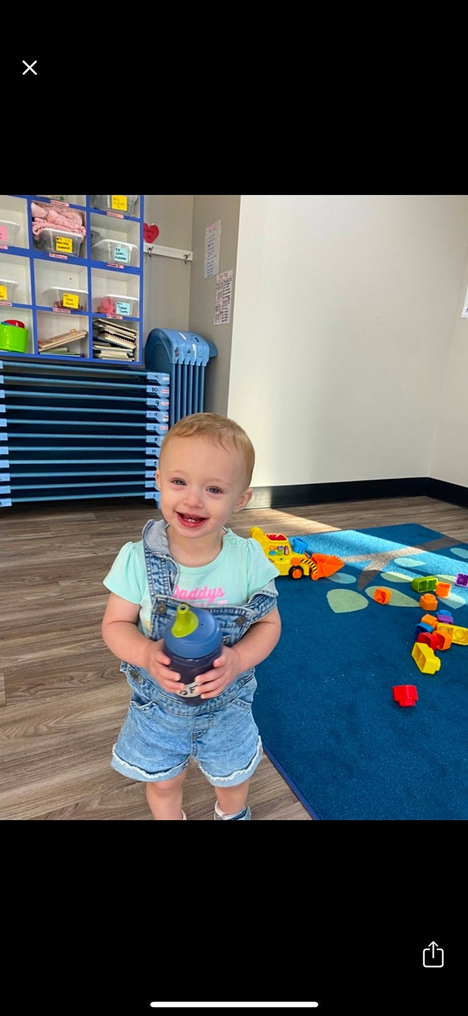 Aribella is registered to the contest to win money with this photo: baby, baby_toddler_clothing, child, floor, flooring, fun, happy, hardwood, joy, leisure, person, play, room, shelf, shorts, sitting, skin, smile, standing, t_shirt