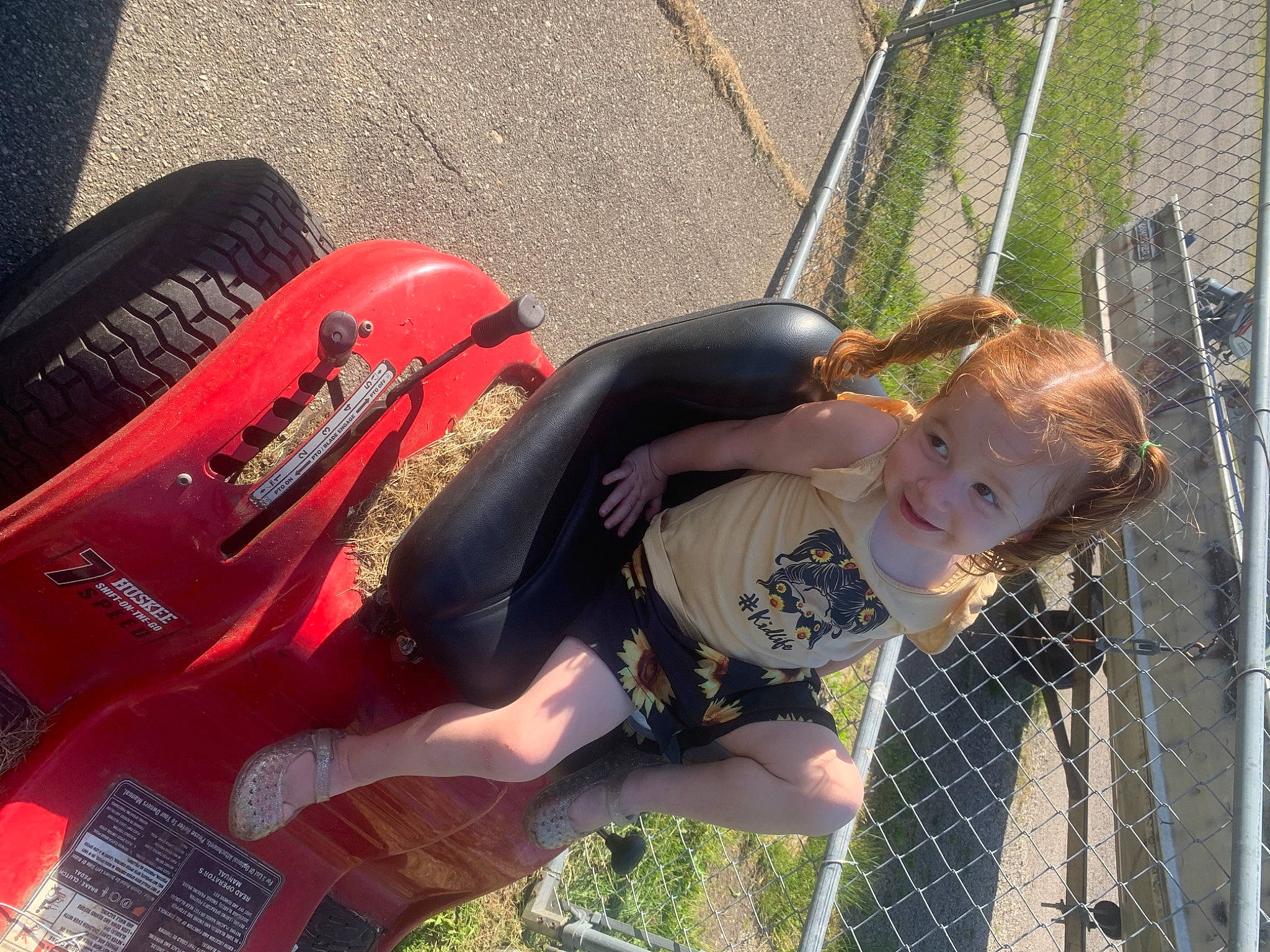 Rosalie is registered to the contest to win money with this photo: automotive_exterior, automotive_lighting, automotive_tire, bumper, fence, fender, fun, grass, joy, leisure, mesh, motor_vehicle, motorcycle, person, personal_protective_equipment, recreation, tire, toddler, vehicle, vehicle_door