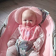 Ivy is registered to the contest to win money with this photo: baby, infant, smiling, pink, bib, baby_chair, pajamas, floral_pattern, face, person, seated, indoors, wooden_floor, cute, child, soft_toys, plush, comfort, happy, portrait