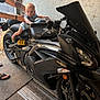 Dino joined the competition — help win amazing prizes! baby, motorcycle, garage, tattoos, person, vehicle, black, floor, handlebar, child, indoor, footwear, head, grip, curious, seat, machine, adult, hand, light