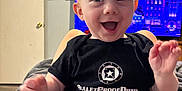 Dino joined the competition — help win amazing prizes! baby, background, balloon, child, clothing, cozy, drawing, expression, face, furniture, happy, home, indoor, legs, light, person, shirt, sitting, smiling, television
