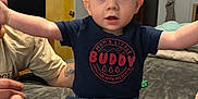 Dino is registered to the contest to win money with this photo: arms, baby, bed, child, clothing, expression, face, feet, furniture, hat, home, indoor, legs, person, photograph, shirt, shorts, surprised, tattoo, wall