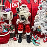 santa_claus, dog, pug, christmas, holiday, sweater, stockings, gift, present, white_christmas_tree, plush_toy, decorations, indoor, festive, red, green, white, person, glasses, chair