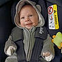 baby, infant, car_seat, hooded_outfit, smiling, child, seatbelt, plush_toy, cozy, cute, young, person, clothing, safety, car, transportation, happy, indoors, portrait, warm