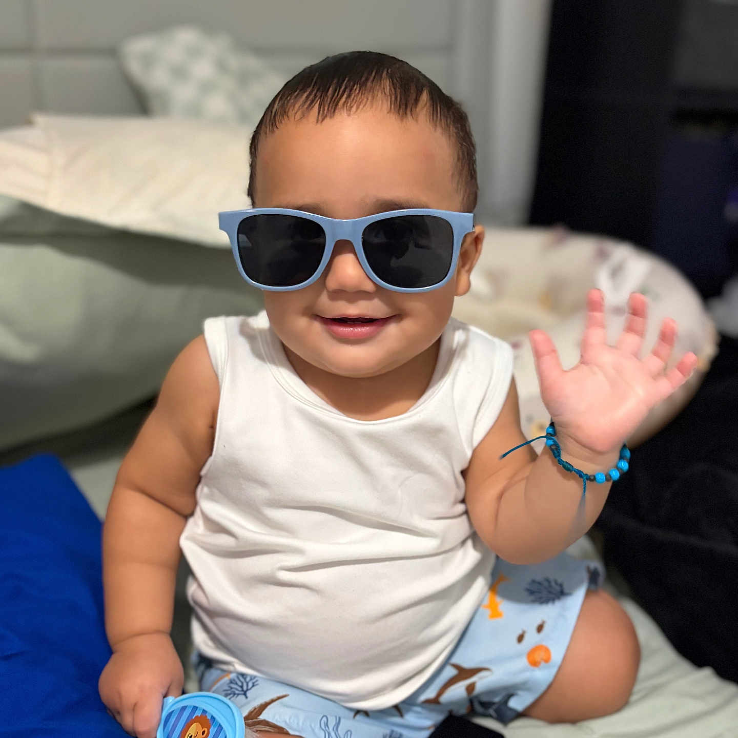 Aiden joined the competition — help win amazing prizes! toddler, child, sunglasses, smile, wave, white_tank_top, blue_shorts, bracelet, brush, bed, pillow, shoes, indoor, cute, happy, baby, person, casual, accessory, playful