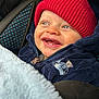baby, child, smile, red_hat, blue_jacket, blanket, car_seat, happy, teeth, face, warm_clothing, knit_hat, infant, portrait, closeup, cute, cozy, blue_eyes, zipper, fabric