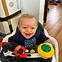 Noah is registered to the contest to win money with this photo: baby, blue_shirt, cardboard_box, eyes, face, hands, happy, hardwood_floor, high_chair, home, indoors, infant, living_room, playtime, seat, smiling, teeth, toddler, toy, walker