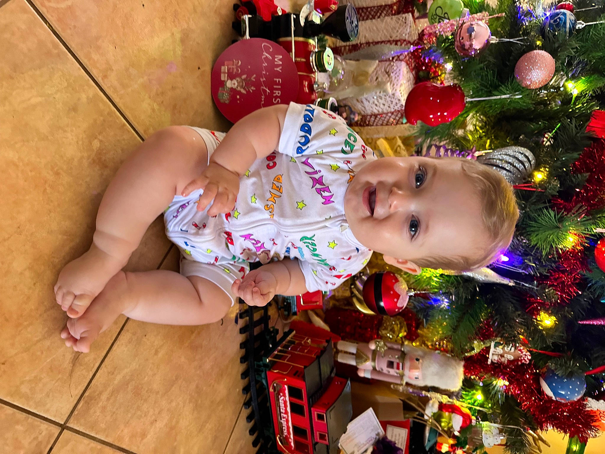 Wayne joined the competition — help win amazing prizes! baby, baby_toddler_clothing, child, christmas_decoration, christmas_ornament, christmas_tree, event, flooring, fun, happy, hardwood, holiday, holiday_ornament, human_leg, joy, leisure, ornament, person, sitting, thigh