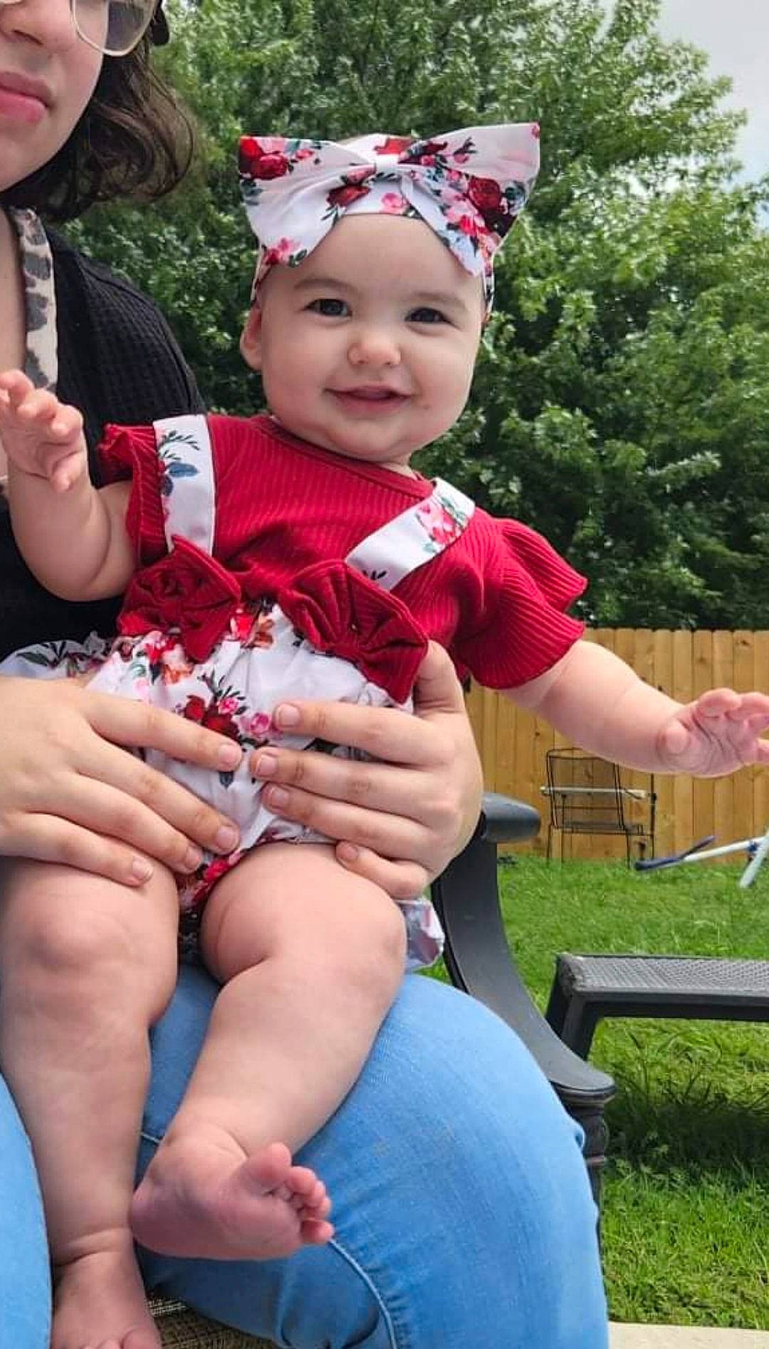 Esmeralda is registered to the contest to win money with this photo: baby_toddler_clothing, child, event, facial_expression, fun, grass, happy, headwear, human_leg, joy, lap, leisure, magenta, person, pink, plant, red, sitting, smile, summer