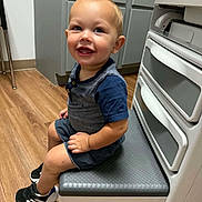 Briggs joined the competition — help win amazing prizes! appliance, blond_hair, blue_clothing, child, face, full_body, happy, home, indoor, kitchen, laundry_room, photograph, portrait, seated, shorts, smiling, sneakers, toddler, washing_machine, wood_floor