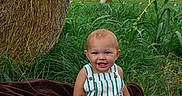 Briggs is registered to the contest to win money with this photo: baby, balloons, barefoot, blanket, child, clouds, corn_field, farmland, grass, greenery, hay_bale, hills, outdoor, overalls, portrait, rural_landscape, seated, sky, smiling, striped_clothing