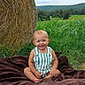 Briggs is registered to the contest to win money with this photo: baby, blanket, child, cornfield, countryside, daylight, farm, grass, greenery, happy, hay_bale, infant, landscape, outdoor, overalls, portrait, rural, sitting, smiling, striped_clothing