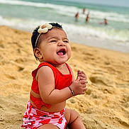 Prayah joined the competition — help win amazing prizes! baby, beach, sand, ocean, water, waves, smiling, child, headband, red_clothing, summer, vacation, happy, sitting, cute, outdoor, nature, sunny, playful, toddler