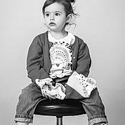 Clementine a rejoint le concours — aidez-le/la à gagner de superbes lots ! toddler, child, jeans, cardigan, sneakers, shirt, stool, black_and_white, portrait, indoor, curly_hair, casual_clothing, footwear, sitting, young_child, expression, curious, studio, fashion, cute