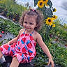 casual_clothing, child, curly_hair, daylight, field, flowers, garden, girl, greenery, growth, nature, outdoor, plants, playful, smiling, sneakers, strawberry_print, summer, sunflowers, vegetation