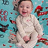 Waylon is registered to the contest to win money with this photo: baby, smiling, striped_pajamas, blanket, cartoon_dogs, hearts, sitting, happy, child, indoors, cute, face, young, infant, soft_texture, patterned, colorful, cozy, comfort, portrait