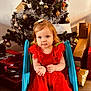 bauble, bow, child, christmas_tree, decoration, festive, gift, holiday, indoor, ornament, portrait, present, red_dress, ribbon, shoes, slide, tinsel, toddler, toy, wooden_floor