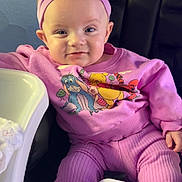 Izabel is registered to the contest to win money with this photo: baby, child, purple_outfit, headband, winnie_the_pooh, high_chair, smiling, infant, cute, seated, indoors, clothing, person, face, apparel, toddler, expression, comfort, soft_lighting, playful