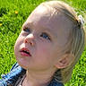 child, toddler, denim_jacket, blonde_hair, blue_eyes, outdoor, grass, dandelions, greenery, sunlight, nature, portrait, casual_clothing, hair_clip, cute, curious, young_child, daylight, face, looking_up