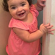 Alyana Rocha joined the competition — help win amazing prizes! toddler, child, smiling, curly_hair, pink_dress, barefoot, door_frame, indoor, happy, cute, baby, person, skin, face, hand, foot, standing, portrait, young_child, expression