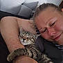person, kitten, cat, sleeping, arm, bed, headboard, closeup, cuddle, indoor, resting, comfort, striped_cat, human_face, relaxation, pet, feline, cozy, affection, casual