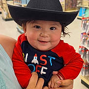 Alexander joined the competition — help win amazing prizes! baby, child, cowboy_hat, smile, red_clothing, onesie, person, indoor, store, aisle, hand, holding, cute, face, young_child, toy_store, colorful, clothing, happy, portrait