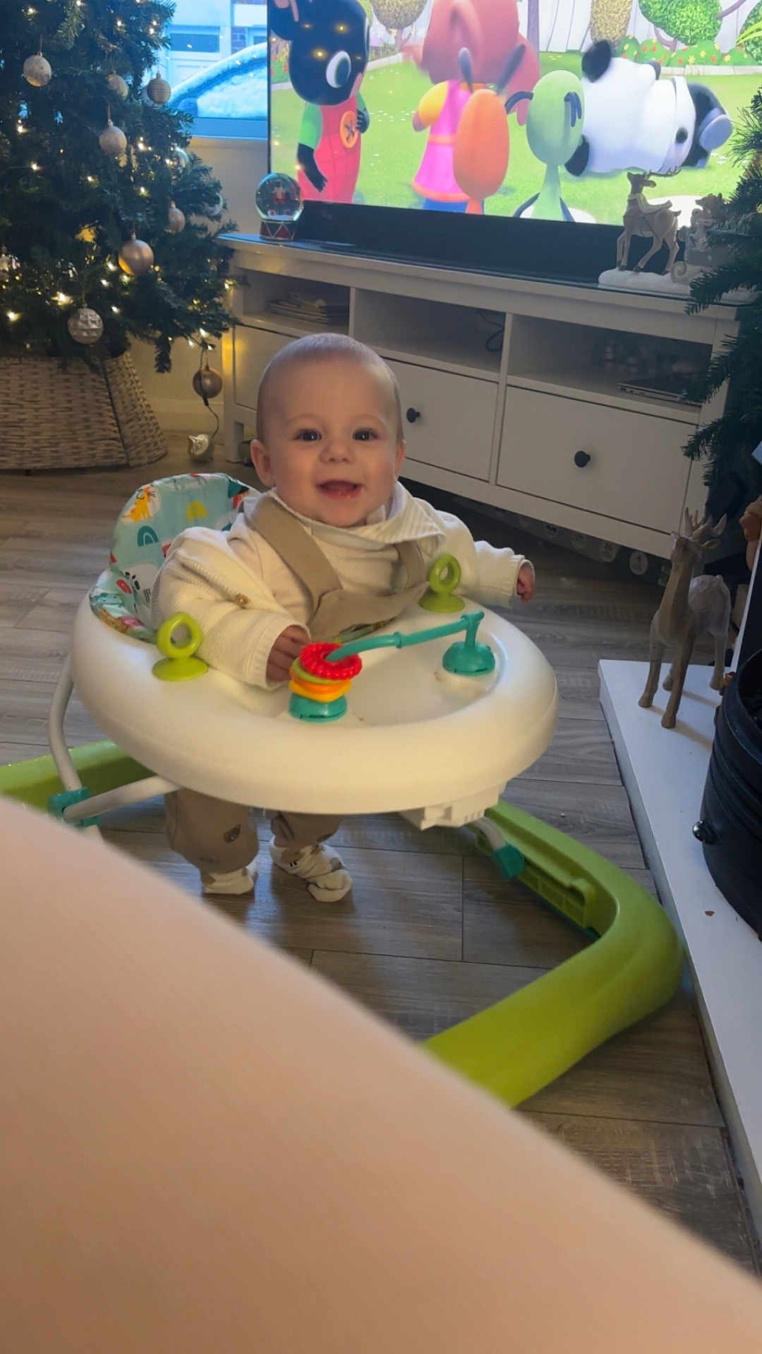 Ronan joined the competition — help win amazing prizes! baby, walker, smiling, indoor, christmas_tree, holiday_decor, toy, flooring, television, cartoon, furniture, wood_floor, person, child, decorations, reindeer_figurine, home, happy, cute, living_room