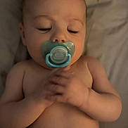 Ronan is registered to the contest to win money with this photo: baby, pacifier, sleeping, hands, skin, lying_down, infant, child, face, human, closeup, bed, blanket, soft_light, peaceful, indoors, portrait, cute, resting, newborn