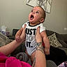 Andre joined the competition — help win amazing prizes! baby, child, infant, onesie, tattoo, arm, hand, living_room, couch, pillow, blanket, wall_art, expression, open_mouth, looking_up, person, indoor, skin, clothing, happy