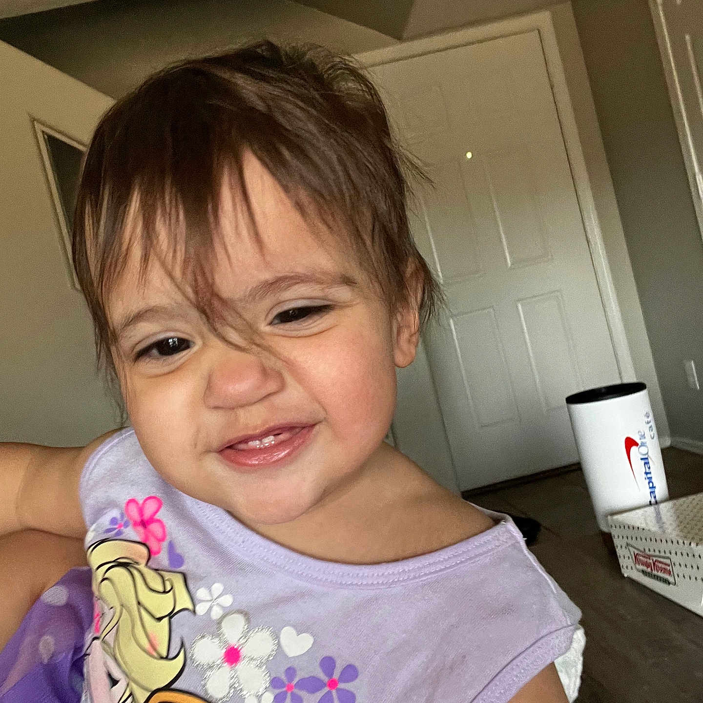 Lyett is registered to the contest to win money with this photo: box, casual, cheeky, child, clothing, cup, disney_frozen, door, face, floor, hair, happy, indoor, mischievous, person, portrait, purple_shirt, smiling, toddler, young_child