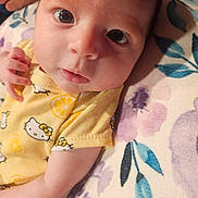 Isabella is registered to the contest to win money with this photo: baby, infant, face, eyes, yellow_clothing, hello_kitty, onesie, hand, blanket, floral_pattern, cute, portrait, newborn, skin, person, lying_down, soft_texture, indoors, closeup, child