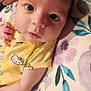 baby, infant, face, eyes, yellow_clothing, hello_kitty, onesie, hand, blanket, floral_pattern, cute, portrait, newborn, skin, person, lying_down, soft_texture, indoors, closeup, child